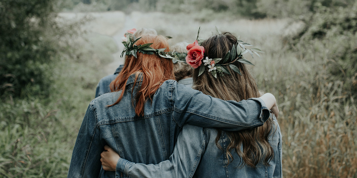 two young women with flowers in their hairarm and arm walking